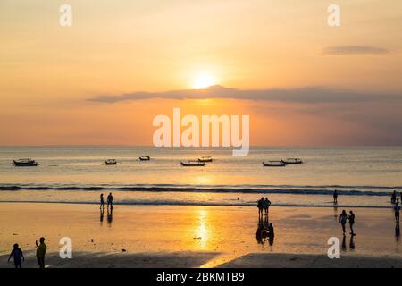 BALI, INDONESIEN - 14. APRIL 2017: Menschen am Kuta Strand in Bali bei Sonnenuntergang. Stockfoto