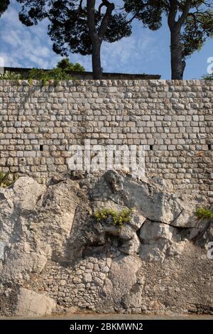Große helle Kalksteinfelsen mit einer Kalksteinmauer in Dubrovnik, Dalmatien, Kroatien an einem sonnigen Tag und einem blauen Himmel. Ru Stockfoto