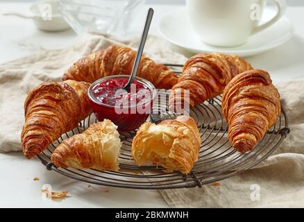 Frisch gebackene Croissants und Marmelade auf dem hellen Küchentisch Stockfoto