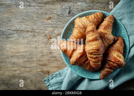 Frisch gebackene Croissants auf einem alten Holztisch, Blick von oben Stockfoto