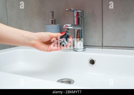 Drehdüse am Mischer zur Einstellung des Wasserflusses. Weißes Waschbecken im Badezimmer zum Händewaschen Stockfoto