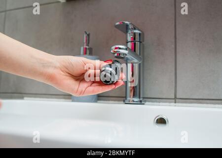 Drehdüse am Mischer zur Einstellung des Wasserflusses. Weißes Waschbecken im Badezimmer zum Händewaschen Stockfoto