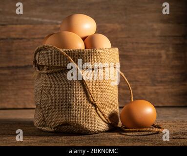 Schließen Sie Ei in Baumwollsack auf Holztisch Hintergrund. Stockfoto