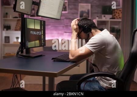 Seitenansicht des Spiels für den Mann mit Kopfhörern spielen Shooter-Spiele im Zimmer mit Neonlicht. Stockfoto