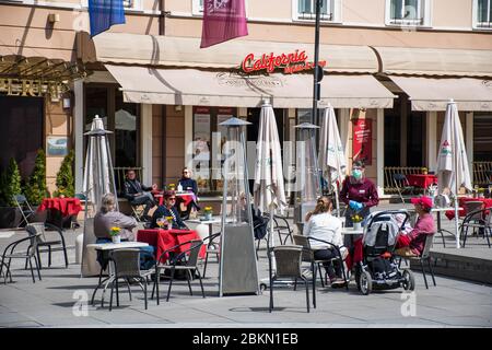 Bar und Restaurant im Freien mit Kunden und Kellnerin mit Maske und Handschuh in Vilnius, der litauischen Hauptstadt, die sich wieder in eine riesige Open-Air-Cafestadt öffnet Stockfoto