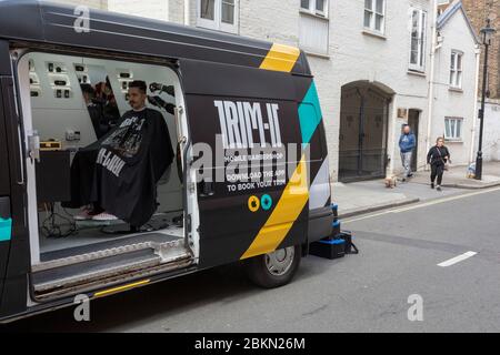 Zu Beginn einer weiteren Woche der Sperrung der Coronavirus-Pandemie, wenn die Regierung ihre Optionen für eine schrittweise Öffnung des Geschäfts mit sozialer Distanz erwägt, sitzt ein männlicher Kunde im Stuhl des App-basierten mobilen Barbershops Trim-IT, Für Kunden, die einen maßgeschneiderten Haarschneidservice benötigen, der am 4. Mai 2020 an ihre Londoner Türschwelle in Pimlico, London, England, geliefert wird. Stockfoto