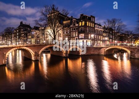Stimmungsvolle Aussicht auf die berühmten Amsterdamer Kanäle und traditionellen holländischen Häuser in der größten Stadt der Niederlande bei Nacht. Aufnahme als Langbelichtung t Stockfoto