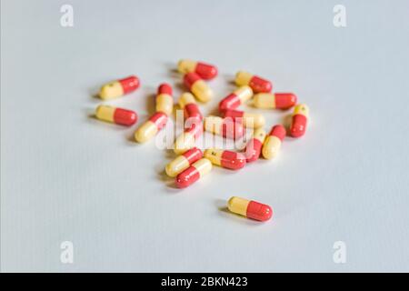 Ein kleiner Haufen von gelben und roten medizinischen Kapseln, eine Kapsel getrennt, auf einem weißen Tisch angezeigt Stockfoto