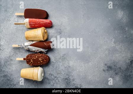 Schokoladeneis Eis Eis Eis und Fruchteis mit Zapfen auf grauem kalten Stein Hintergrund. Platz für Text kopieren. Stockfoto