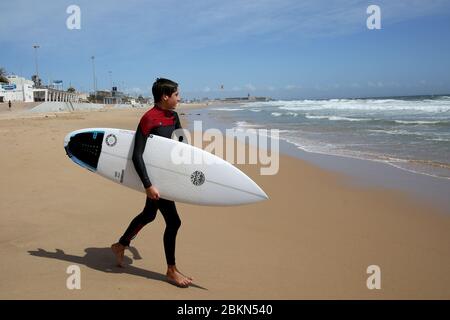 (200505) -- LISSABON, 5. Mai 2020 (Xinhua) -- EIN Surfer spaziert am Carcavelos Strand in der Nähe von Lissabon, Portugal, 4. Mai 2020. Portugal begann am Montag nach fast 50 Tagen der Blockierung im Ausnahmezustand aufgrund der COVID-19-Pandemie, seine Wirtschaft und Gesellschaft wieder zu beleben. In der ersten Phase der dreistufigen Entkäuung von Montag bis Mai 18 dürfen Gewerbezentren bis zu 200 Quadratmetern und Straßengeschäfte mit strengen sanitären Maßnahmen wieder eröffnet werden. (Foto von Pedro Fiuza/Xinhua) Stockfoto