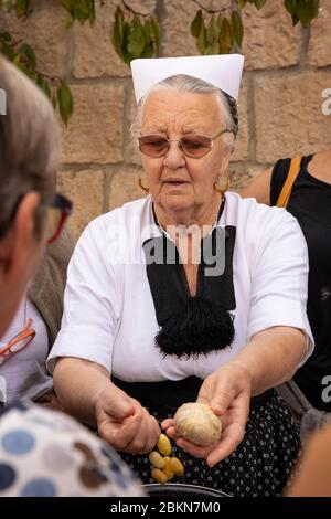 Konavle, Kroatien, 5. September 2019. Eine ältere Frau, die ein tranditional altes Folklore-Kostüm trägt, das den Menschen zeigt, wie organische Seide in einem ru hergestellt wird Stockfoto