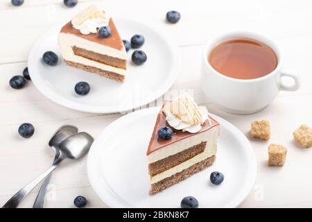 Kuchen mit Sahne auf dem Tisch, neben einem Kuchen mit Blaubeeren und Tee in einer Tasse Stockfoto