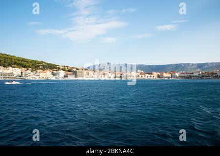 Der Hafen von Split vom Meer aus gesehen, mit Booten, die vorbeikommen und einem sehr blauen Meer an einem sonnigen Tag im Sommer, was eine achtsame idyllische Landschaft schafft Stockfoto