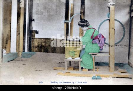 [ 1910er Japan - Japanische Seidenfarm ] - EINE Frau in Yukata und traditioneller Frisur ist das Aufspinnen von Seide aus Kokons. Diese Postkarte stammt aus einer Serie über die Serikultur, die die Schritte zeigt, die bei der Seidenherstellung erforderlich sind. Dies ist Karte 12. Vintage-Postkarte des 20. Jahrhunderts. Stockfoto