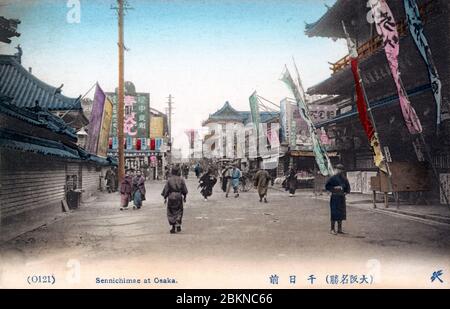 [ 1900er Japan - Sennichimae Entertainment District, Osaka ] - Menschen unter Flaggen in Sennichimae, Osaka. Seit der Edo-Periode (1603-1868) war Sennichimae zusammen mit Dotonbori Osaka das Hauptunterhaltungs-Viertel. Vintage-Postkarte des 20. Jahrhunderts. Stockfoto