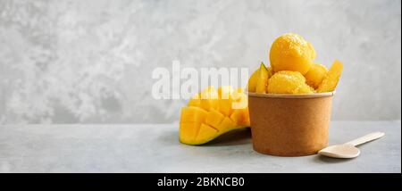 Erfrischendes Mangoeis in einer Papiertasse auf grauem Hintergrund Stockfoto