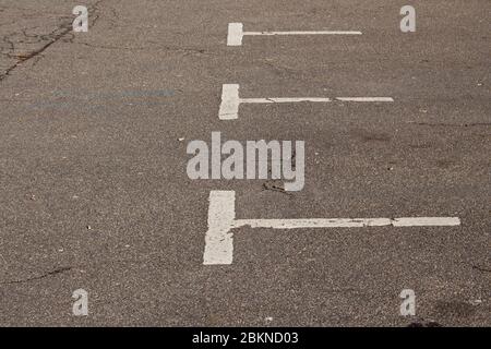 Alte, schmutzige und verblassende weiße Markierungen auf einem leeren Parkplatz Stockfoto