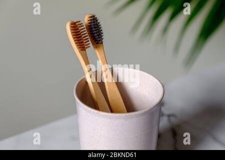 Becher mit Bio-Bambus-Zahnbürsten auf dem Tisch, Nahaufnahme. Zahnärztliche Versorgung Konzept. Stockfoto