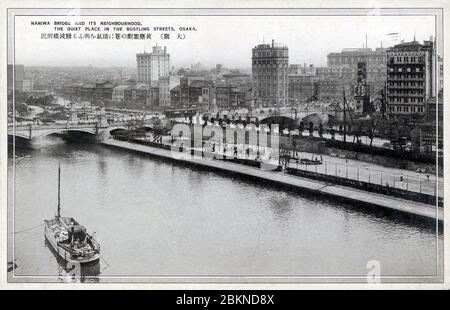 [ 1920er Jahre Japan - Naniwabashi Brücke, Osaka ] - Naniwabashi Brücke überspannt den alten Yodo Fluss und wurde 1915 fertiggestellt (Taisho 4). Die Brücke war und ist bekannt für ihre Laternenpfosten und Steinstatuen von Löwen. Es verfügte über beeindruckende Steintreppen, die zur Insel Nakanoshima und dem Uferpark führten, der zum Zeitpunkt der Brückenerbauung im Bau war. Vintage-Postkarte des 20. Jahrhunderts. Stockfoto