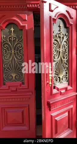 Geöffnete rote Doppeltür mit verzierten Rahmen und gebogenen Metallgittern. Erbe der historischen Gebäude in der europäischen Stadt Odessa der Ukraine Stockfoto