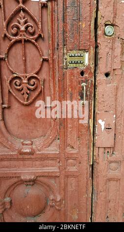 Beschädigte Oberfläche der alten Holztür mit verzierten Gitterfragment und Retro-Schloss der Gegensprechanlage Tastatur. Grunge Details des verfallenen Gebäudes en Stockfoto