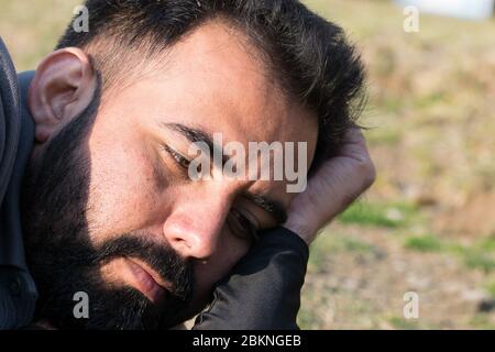 Ehrliche Nahaufnahme eines bärtigen jungen Mannes, der wegschaut Stockfoto