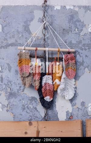 Ein trendiger macrame handgemachte Wand hängen aus bunten Baumwollfedern hängen an einer rustikalen Betonwand in einem Loft-Interieur. Öko-Handstück im Hippie-Stil Stockfoto