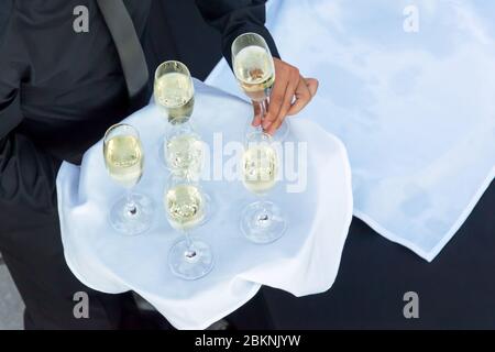 Von oben gesehen, dass ein Kellner ein Tablett mit Gläsern Champagner oder weißen Gewinnen hält, und Getränke auf einer Cocktailparty serviert Stockfoto