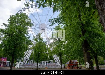 05. Mai 2020, Sachsen-Anhalt, Magdeburg: Zwischen den Bäumen des Rotehornparks steht ein Riesenrad. Derzeit arbeiten die Betreiber ein Konzept aus, um die Abstandsregeln einzuhalten. An der Basis hat bereits eine Snackbar geöffnet und Lebensmittel verkauft. Essen ist jedoch nicht im Umkreis von 50 Metern erlaubt. Das Riesenrad wurde in den vergangenen Wochen aufgebaut und wird von den Gebrüdern Boos aus Magdeburg betrieben. Eigentlich sollte die Fahrt im Moment auf anderen Messen betrieben werden. Sie waren jedoch wegen der Ausbreitung des Corona-Virus abgesagt worden. Jetzt ist das Riesenrad in der Landeshauptstadt an Stockfoto