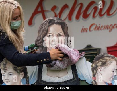 Aschau Im Chiemgau, Deutschland. Mai 2020. Stefanie Sattlberger, Geschäftsfrau für Tourismus und Freizeit, wischt das neu gemalte Porträt von Ilse Aigner (CSU), Präsidentin des Bayerischen landtags, für eine Fotosession mit einem Handtuch trocken. 2014 schenkte Aigner die Bank mit dem Namen 'Ilse's Lausdirndlbankerl' dem Chiemgauer Dorf Aschau, auch bekannt als 'Bankerldorf'. Der Politiker war damals Bayerischer Wirtschaftsminister. Quelle: Peter Kneffel/dpa/Alamy Live News Stockfoto