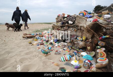 Die Menschen gehen an gemalten Kieselsteinen vorbei, die Unterstützung für den NHS und die Schlüsselarbeiter zeigen und positive Botschaften enthalten, die von den Bürgern am Strand von Avon in Christchurch hinterlassen wurden, während Großbritannien weiterhin in der Blockierung ist, um die Ausbreitung des Coronavirus einzudämmen. Stockfoto