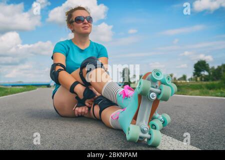 Frau, die in einem Jahrgang Rollschuhe, retro Quad skates Sitzen im Freien. Stockfoto