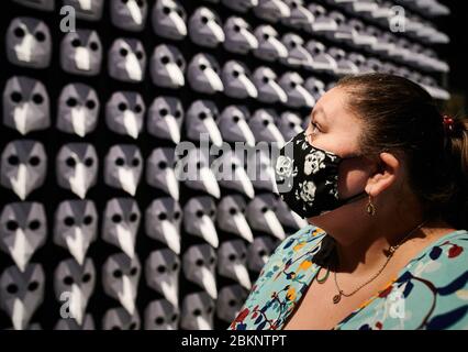 Herdecke, Deutschland. Mai 2020. Die Besucherin Ingrid Cosic, die in der Ausstellung "Pest - SPURENSUCHE" im LWL-Archäologiemuseum eine Gesichtsmaske mit Totenkopf trägt, steht vor einer Ausstellung von 300 sogenannten Pestmasken, die im Mittelalter von Ärzten zeitweise als "Dr." getragen wurden Schnabel' zum Schutz vor Infektion mit der Pest. Die Museen des Landschaftsverbandes Westfalen-Lippe sind ab Dienstag (5.5.) wieder geöffnet. Die Sonderausstellung zur Pest wurde aufgrund der vorherigen Schließung bis zum 15. November verlängert. Quelle: Bernd Thissen/dpa/Alamy Live News Stockfoto