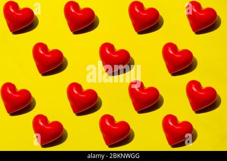 Nahtloses Muster Rote Herzen auf gelbem Hintergrund. Draufsicht, flaches Layout. Romantisches buntes Muster. Stockfoto