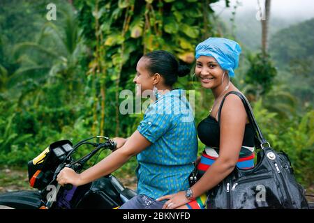 Dominikanische Leute. Zwei Mädchen auf einem Motorrad, vor der Kulisse der Natur der Samana Halbinsel. Dominikanische Republik. 26.01.2013 Stockfoto