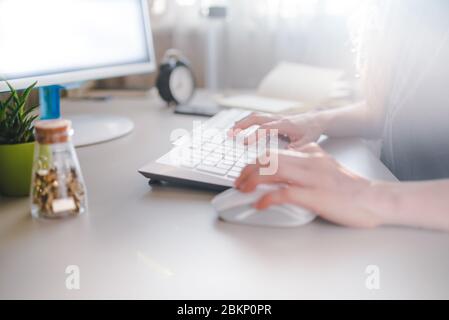 Mädchen tippt auf einer weißen Tastatur und verwendet Maus Stockfoto