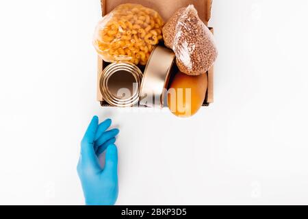 Kontaktloser Satz des fertigen Produktset. Flach legen mit Lebensmittelbox und einer Hand in einem medizinischen Handschuh. Stockfoto