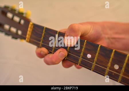 Hand des Mannes, der die alte akustische Gitarre spielt. Alter Gitarrenkopf mit Stimmwirbeln. Stockfoto