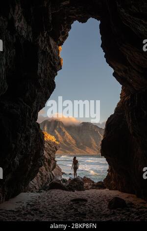 Weibliche posiert in der Mitte der Dappat se Gat Höhle, einem beliebten Strand in Kogel Bay, Kapstadt Südafrika Stockfoto