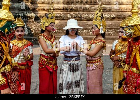 Junge kambodschanische Frauen in traditioneller Tracht im Umgang mit BESUCHERN im Angkor Wat Temple Complex, Siem Reap, Provinz Siem Reap, Kambodscha. Stockfoto