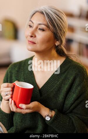 Bild von ernsten reifen schönen grauhaarigen Frau drinnen Kaffee trinken. Stockfoto