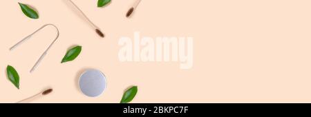 Banner mit Rahmen aus Zubehör für Zahnhygiene und grünen Blättern auf beigem Hintergrund. Plastikfreies Konzept mit Kopierfläche. Stockfoto