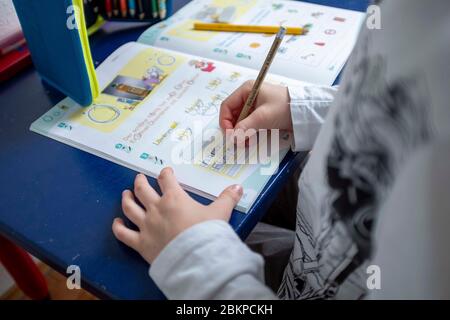 Erstklaessler (7 Jahre) sitzt zu Hause an einem Tisch und erledigt deutsche Aufgaben in seinem Booklet "Alphabet Booklet - BASIC Font", am 4. Mai 2020 in Mülheim an der Ruhr. ¬ Verwendung weltweit Stockfoto