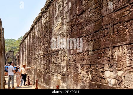 Besucher, Die Die Bas Reliefs Im Bayon Tempel, Angkor Wat Temple Complex, Siem Reap, Kambodscha Besichtigen. Stockfoto