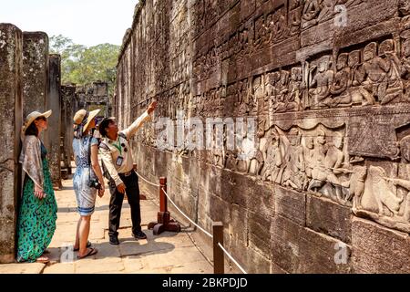 Weibliche Besucher, Die Die Bas Reliefs Im Bayon Tempel, Angkor Wat Temple Complex, Siem Reap, Kambodscha Betrachten. Stockfoto