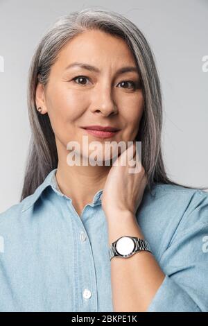 Porträt einer elegant lächelnden schönen reifen Dame mit langen grauen Haaren in lässigen Kleidung stehen isoliert über Hintergrund, Blick auf die Kamera Stockfoto