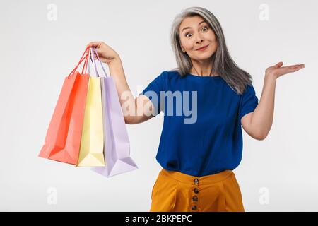 Bild von erwachsenen reifen Frau mit langen grauen Haaren tragen Papier Einkaufstaschen isoliert über weißem Hintergrund Stockfoto