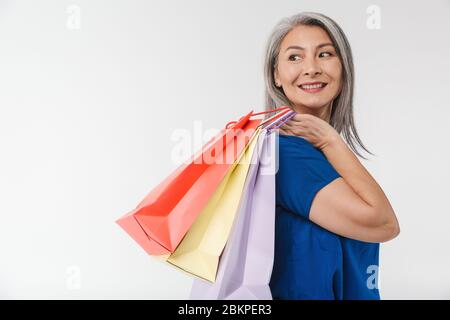 Bild von erwachsenen reifen Frau mit langen grauen Haaren tragen Papier Einkaufstaschen isoliert über weißem Hintergrund Stockfoto