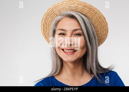 Bild von erwachsenen reifen Frau mit langen grauen Haaren tragen Stroh Sommer Hut posiert bei Kamera isoliert über weißem Hintergrund Stockfoto