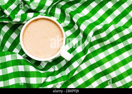 Tasse leckeren Kaffee mit Milch auf einem grünen Hintergrund, Platz für Text. Draufsicht. Stockfoto